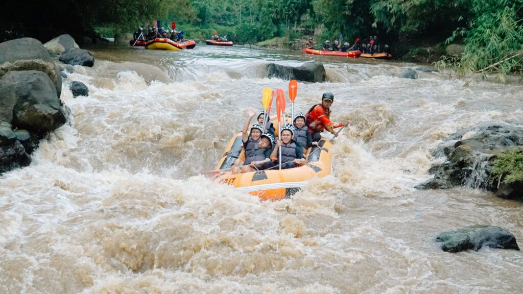Group enjoying thrilling white water rafting down a rocky river with lush greenery.